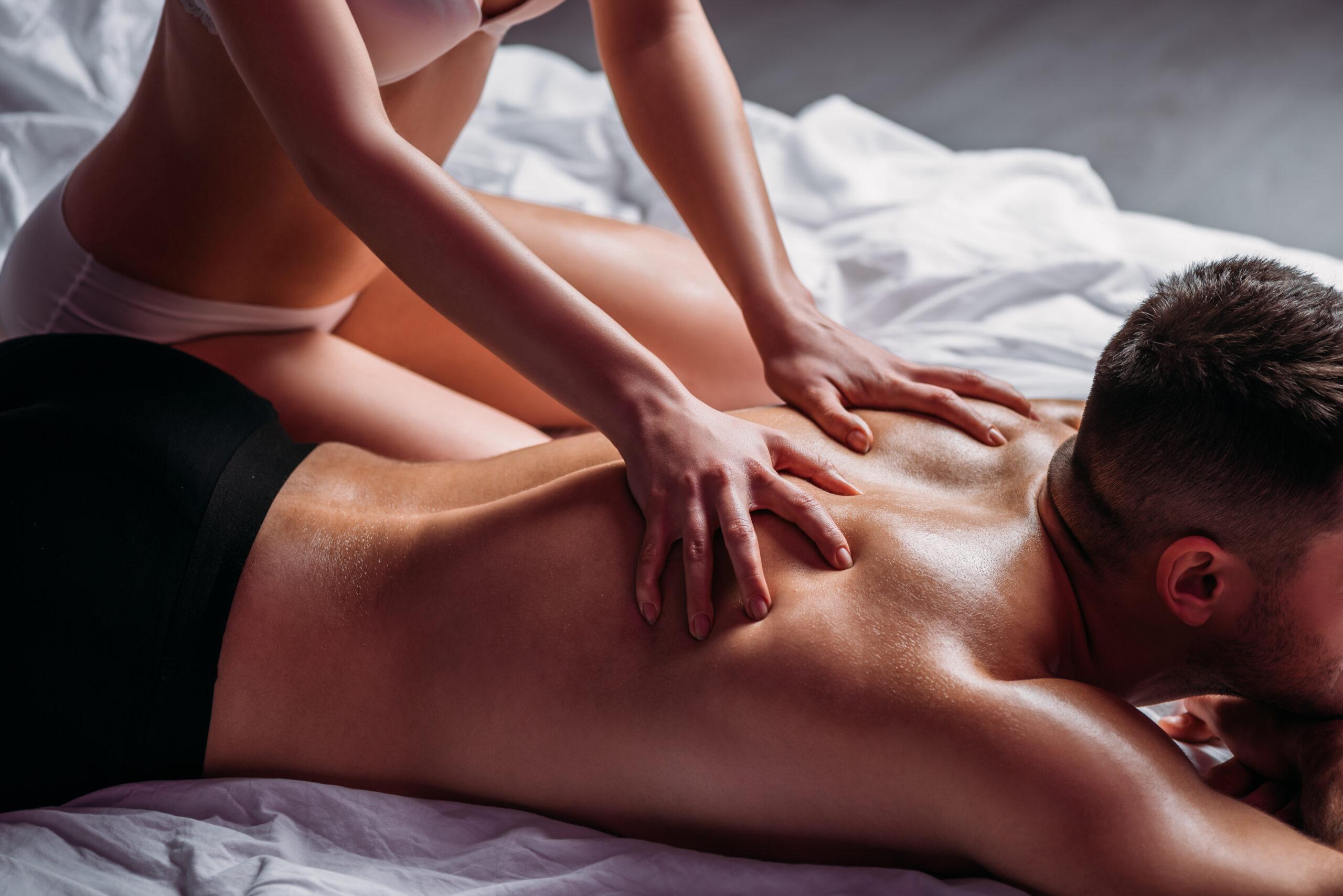 cropped view of girl making back erotic massage to shirtless boyfriend lying on bed